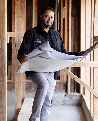 Mario Arechiga reviewing plans on a framed jobsite